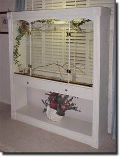 a white shelf with flowers and plants in it