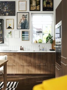 a kitchen with wooden cabinets and pictures on the wall above it, along with a yellow chair