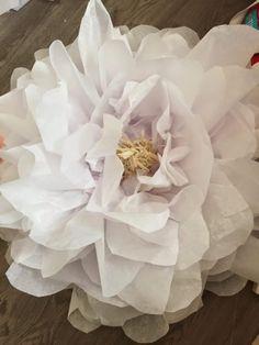 a large white flower sitting on top of a wooden table next to a pair of scissors