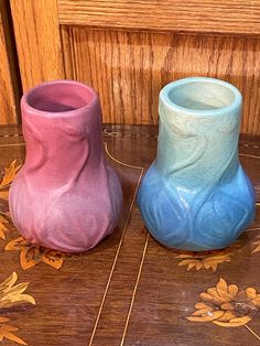 two small vases sitting on top of a wooden table next to each other,