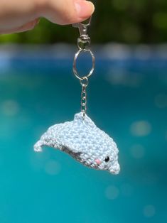 a crocheted dolphin keychain being held by someone