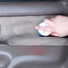 a person is cleaning the back seat of a car with a blue and white brush