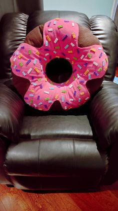 a brown leather chair with a pink donut pillow on it