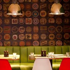 two booths in a restaurant with green booth seats and wallpapered walls behind them