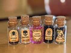 six miniature bottles filled with different types of halloween spices on top of a wooden table