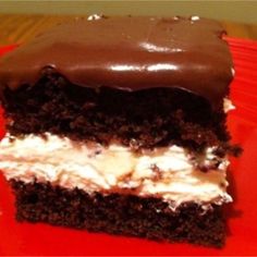 a piece of cake with chocolate frosting and white icing on a red plate