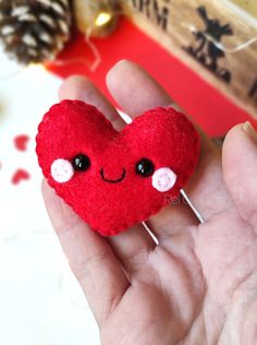 a hand holding a red felt heart with eyes and nose on it's thumb