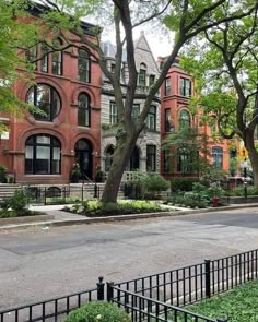 an old brick building with many windows and trees in front of it on a city street