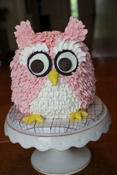 the cake is decorated with pink and white icing, an owl's eyes are visible