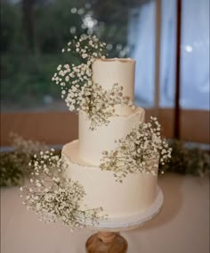 a three tiered wedding cake with baby's breath on top