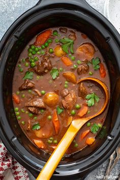 a close up of a pot of stew with carrots, peas and meat in it