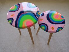 two colorful stools sitting on top of a white carpeted floor next to each other