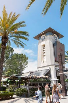 people are walking around in front of a clock tower