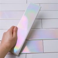 a person is holding a white box with holographics on it and their hand is next to it