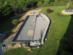 an aerial view of a pool being built in a backyard with green grass and trees