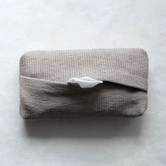 a folded cloth with a tissue paper sticking out of it's side on a white surface