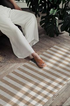 a woman is sitting on the floor with her feet up in front of a potted plant