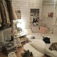 two cats laying on a bed in a room with white brick walls and wooden floors