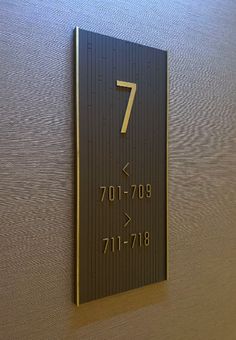 a metal sign with the number seven on it's side next to a wall