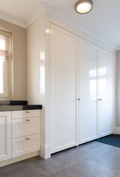 an empty kitchen with white cabinets and black counter tops, along with a blue rug on the floor