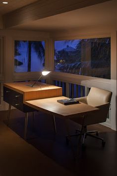 a desk with a lamp on it in front of a window overlooking the ocean at night