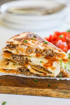 two quesadillas stacked on top of each other with tomatoes and lettuce