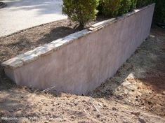 a stone planter sitting on the side of a road next to a tree and bushes