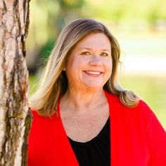 a woman standing next to a tree smiling