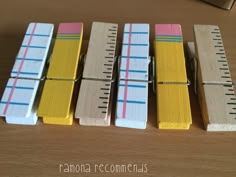 four wooden clothes pins lined up next to each other on top of a wood table