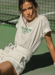 a woman sitting on the ground with a tennis racket