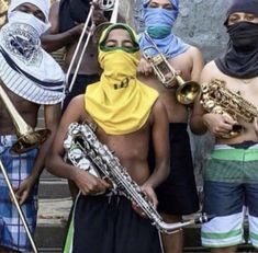 a group of young men standing next to each other holding musical instruments and wearing bandanas