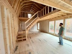 a man standing in the middle of a room with wooden flooring and walls that are being built