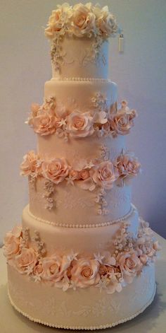 a three tiered wedding cake with pink flowers on top and white frosting around the edges