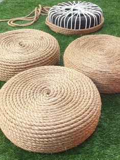 four round baskets sitting on top of green grass next to a rope bag and two black and white striped stools