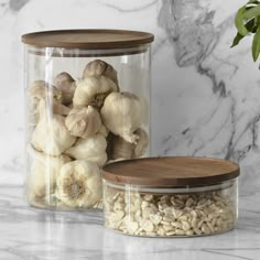 two glass jars filled with garlic on top of a marble counter