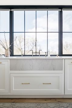 a kitchen with large windows and white cabinets