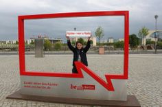 a woman standing in front of a sign with an arrow pointing to the right and holding her hands up