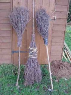 two brooms that are sitting in the grass next to a fence with words written on it