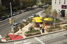 an aerial view of people walking on the sidewalk in front of a restaurant with yellow umbrellas