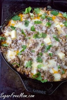 a skillet filled with meat, cheese and cilantro leaves on top of a stove