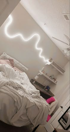 an unmade bed with white sheets and pink pillows