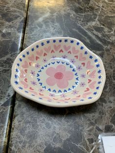 a pink and blue flowered bowl sitting on top of a marble counter