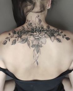 the back of a woman's neck with flowers and leaves tattooed on her shoulder