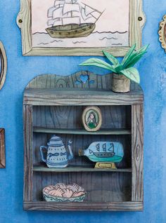 a blue painted wall with an old fashioned bookcase, vase and other items on it