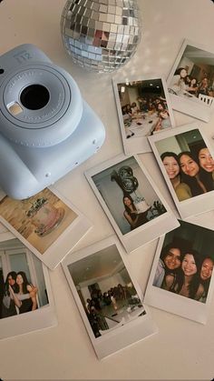 polaroid camera sitting on top of a table with many pictures and a disco ball in the background