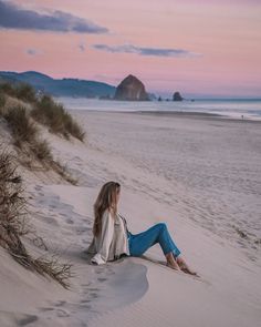 a woman sitting on top of a sandy beach