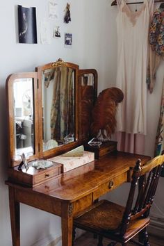 a wooden desk with a mirror, chair and other items on the table in front of it