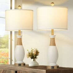 two white lamps sitting on top of a wooden table