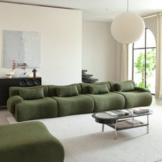 a living room with green couches and white carpeted flooring in front of large windows