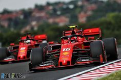 two red race cars driving down the road